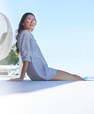 Buy stock photo Shot of a young woman relaxing by the poolside