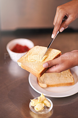 Buy stock photo Cropped shot of a woman spreading butter onto toast