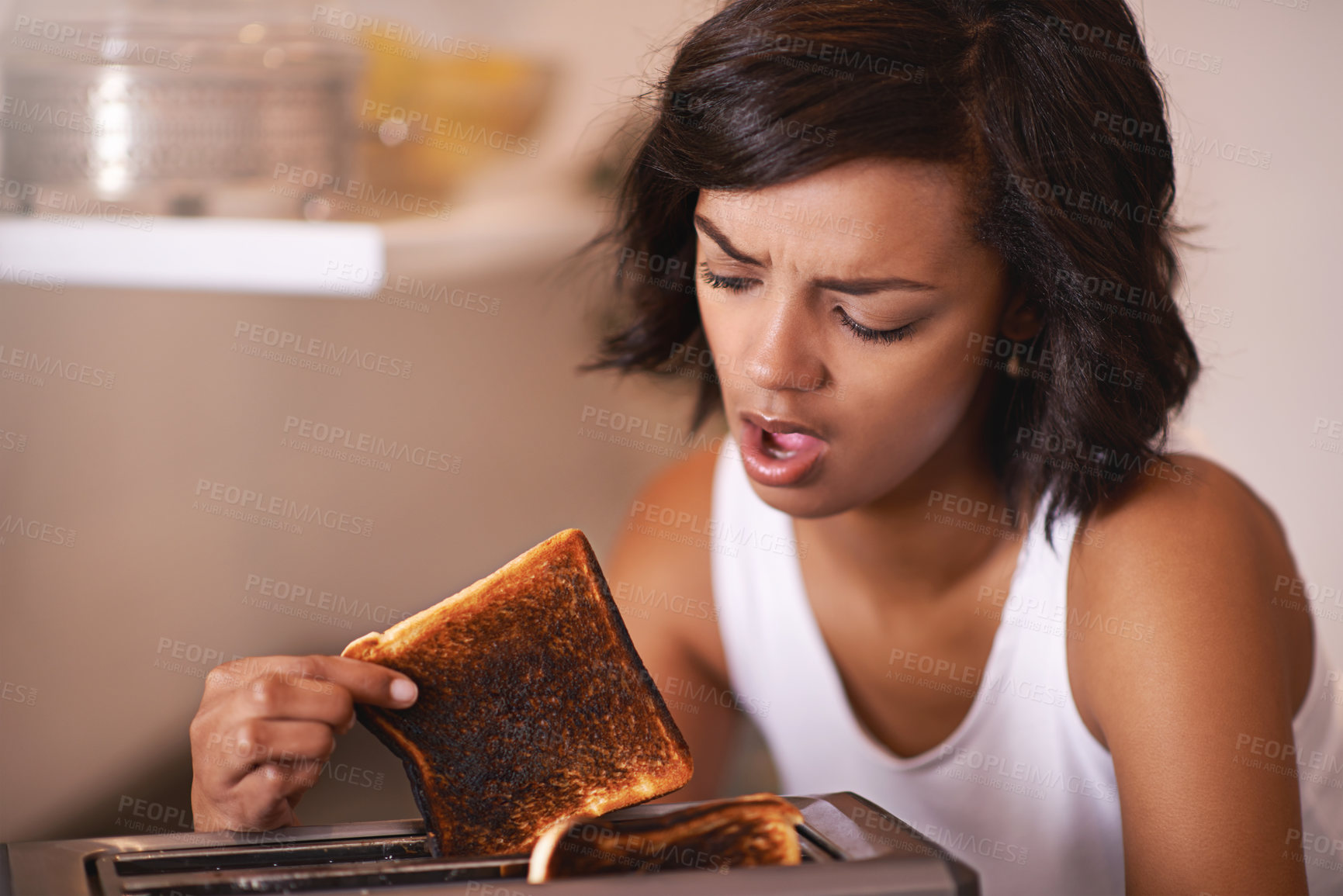 Buy stock photo Cropped shot of a young woman taking a piece of burnt toast from the toaster