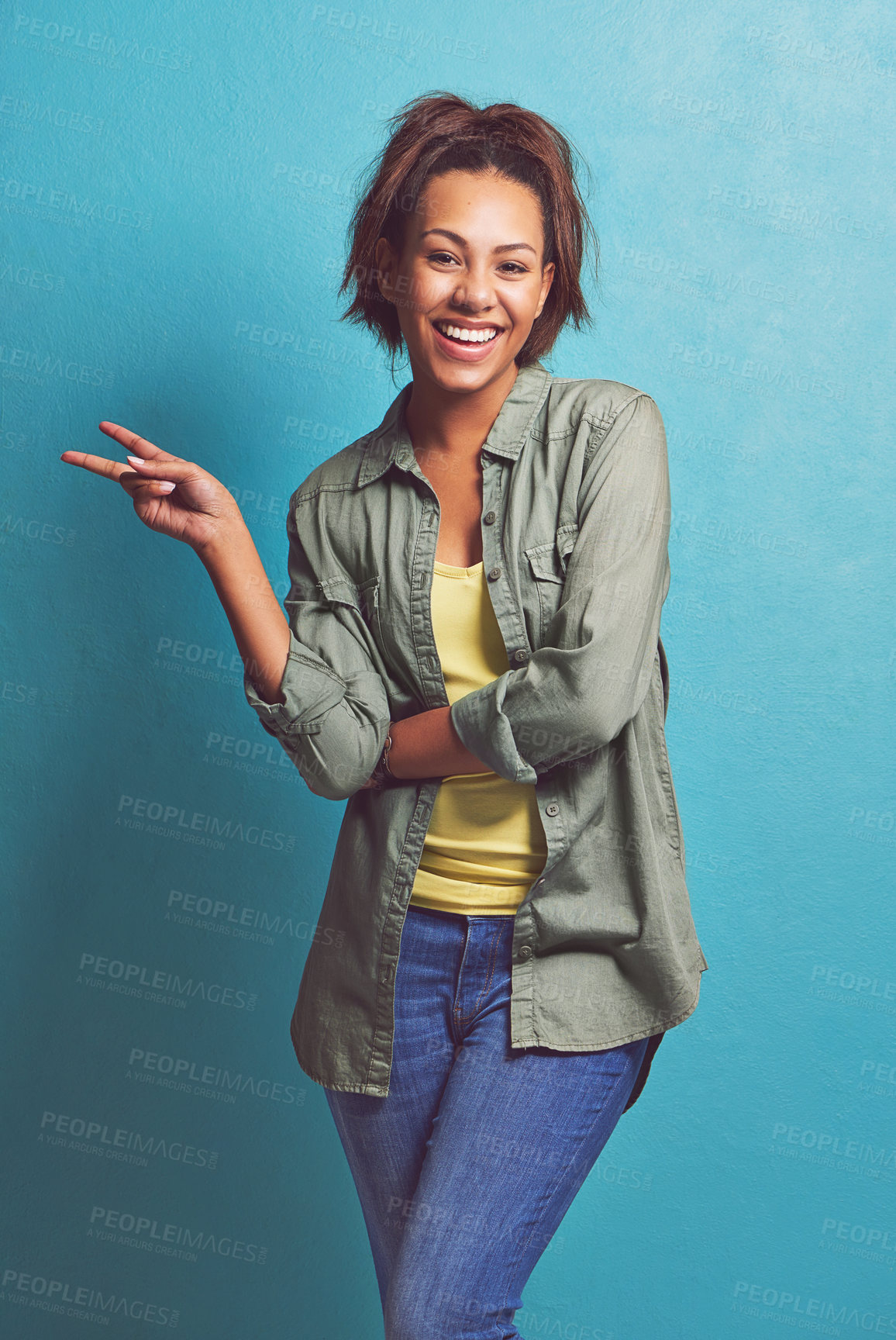 Buy stock photo Portrait of a young woman showing you the peace sign against a blue background