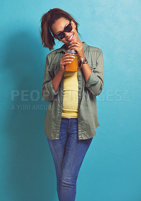 Buy stock photo Happy woman, portrait and sunglasses with orange drink in fashion for vitamin C or diet on a blue studio background. Female person, brunette or model with smile for citrus juice or fresh beverage