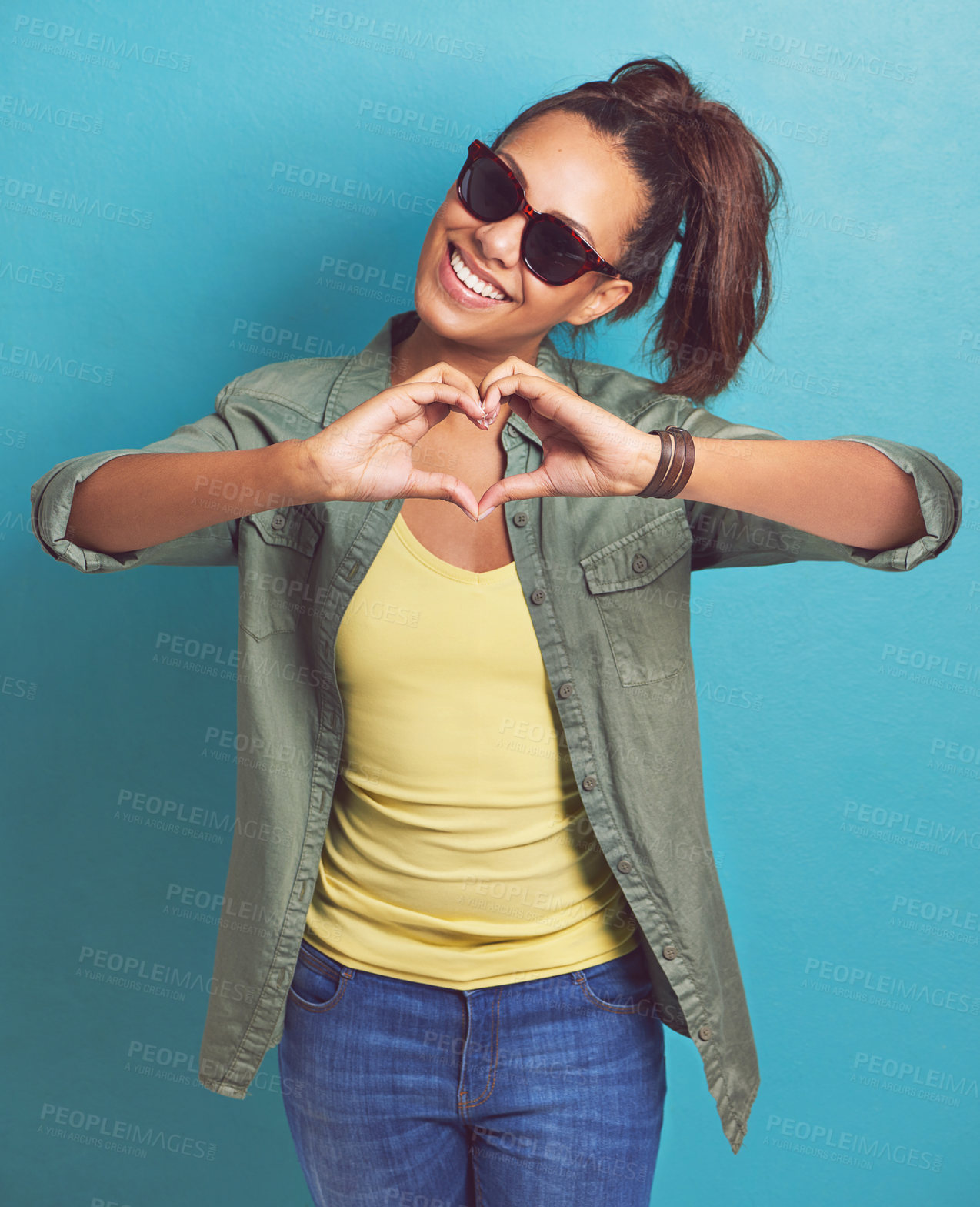 Buy stock photo Shot of a young woman making a heart shape with her hands