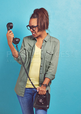 Buy stock photo Shot of a young woman looking irritatedly at a telephone