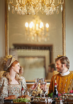 Buy stock photo Shot of a noble couple toasting while eating together in the palace dining room