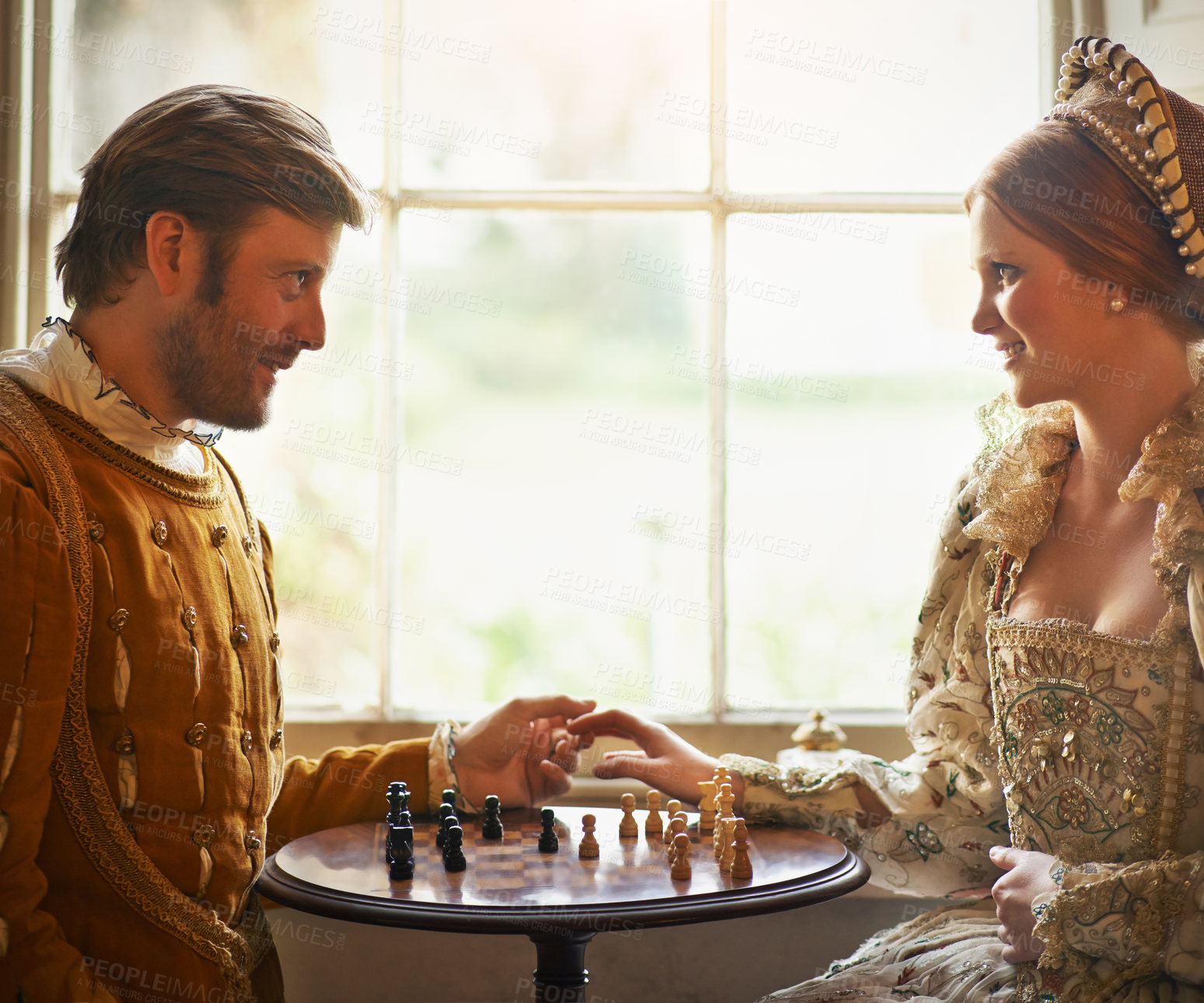 Buy stock photo Renaissance, couple and chess at home with holding hands, vintage and medieval costume in a palace. Window, luxury and queen together with smile from strategy game and talking while playing with love