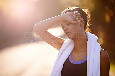 Buy stock photo Shot of a woman wiping away the sweat after some intense outdoor training