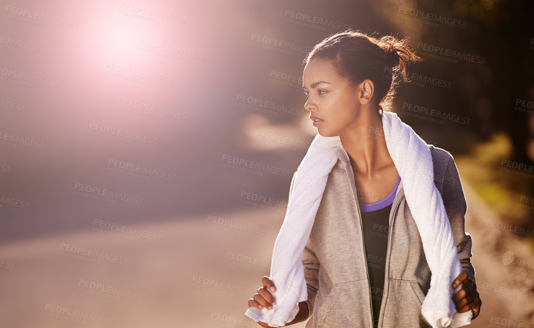 Buy stock photo Shot of a woman holding a towel around her neck after exercising