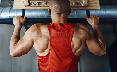 Buy stock photo Rearview shot of a man doing pull-ups at the gym
