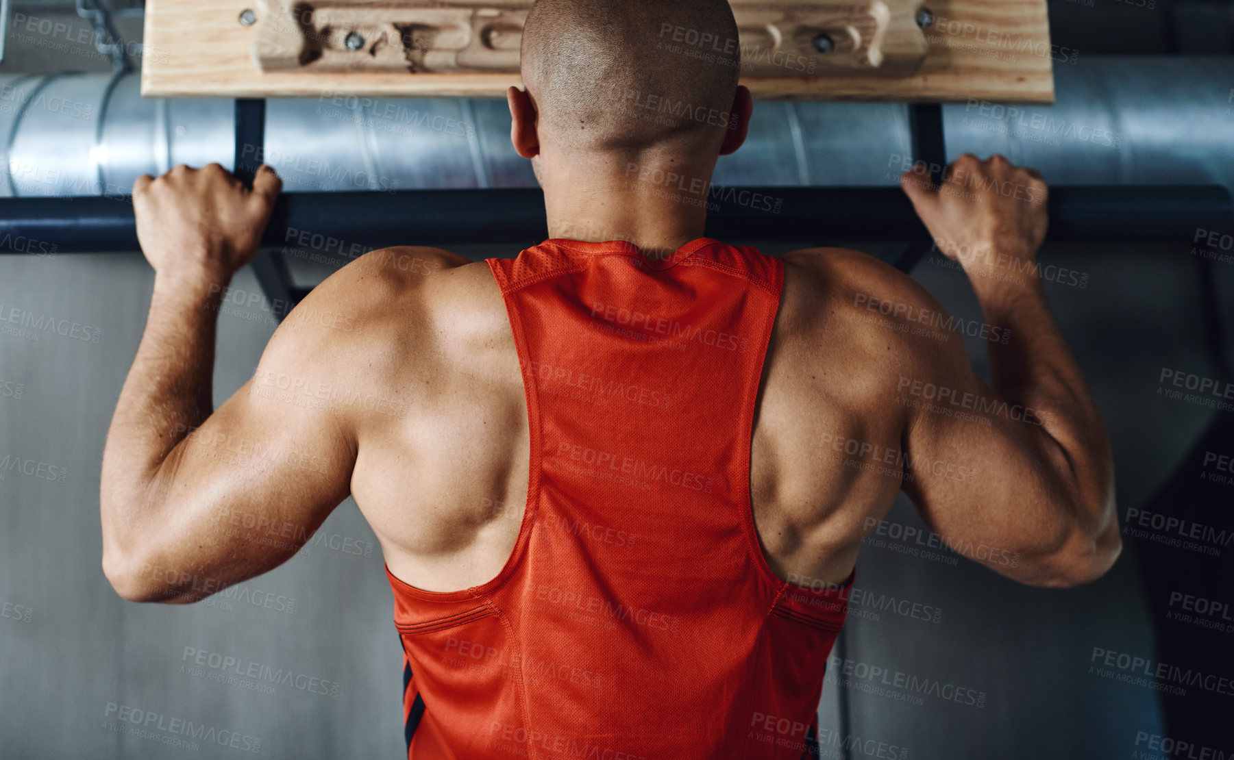 Buy stock photo Rearview shot of a man doing pull-ups at the gym