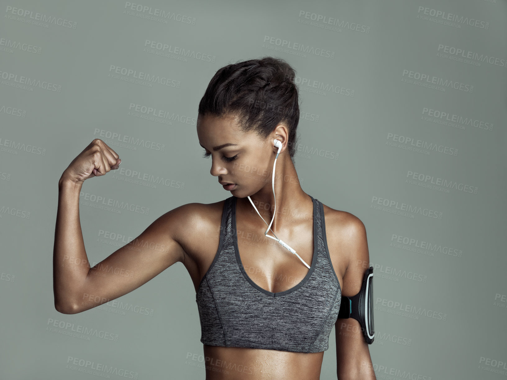 Buy stock photo Woman, strong and muscle flex on studio backdrop for fitness with headphones, music and streaming. Technology, arm and athlete on background for wellness, online and podcast or workout timer