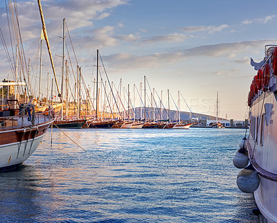 Buy stock photo Group of boats docked in romantic harbor of Bodrum in Turkey at sunset. Scenic view of sailing yachts in cruise port and bay at dusk. Empty dockyard in Aegean sea against cloudy blue sky