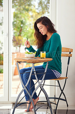 Buy stock photo Shot of a young woman eating a healthy salad at home