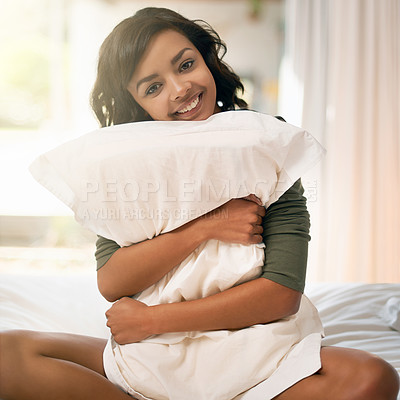 Buy stock photo Shot of a young woman hugging her pillow while sitting on her bed