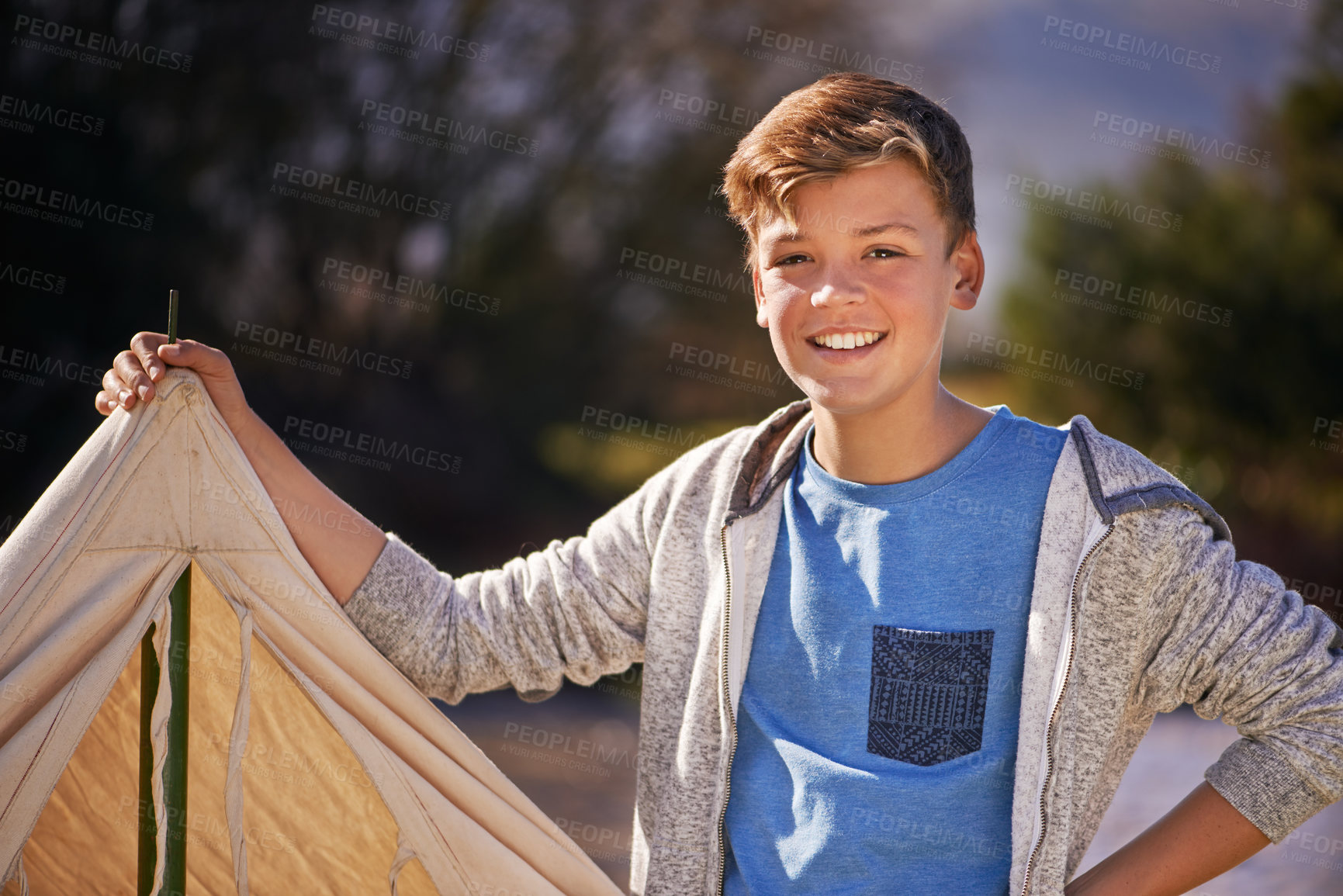 Buy stock photo Shot of a young boy putting up his tent on a camping trip