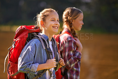 Buy stock photo Shot of two young girls wearing backpacks walking together