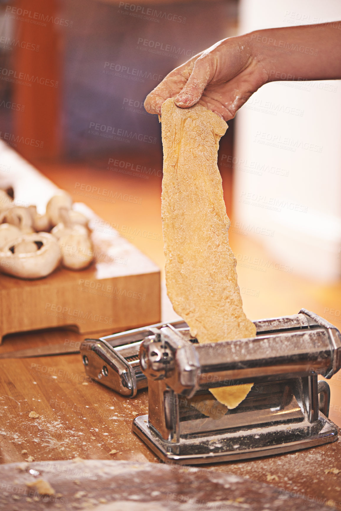 Buy stock photo Cropped shot of a person rolling freshly made dough through a pasta maker