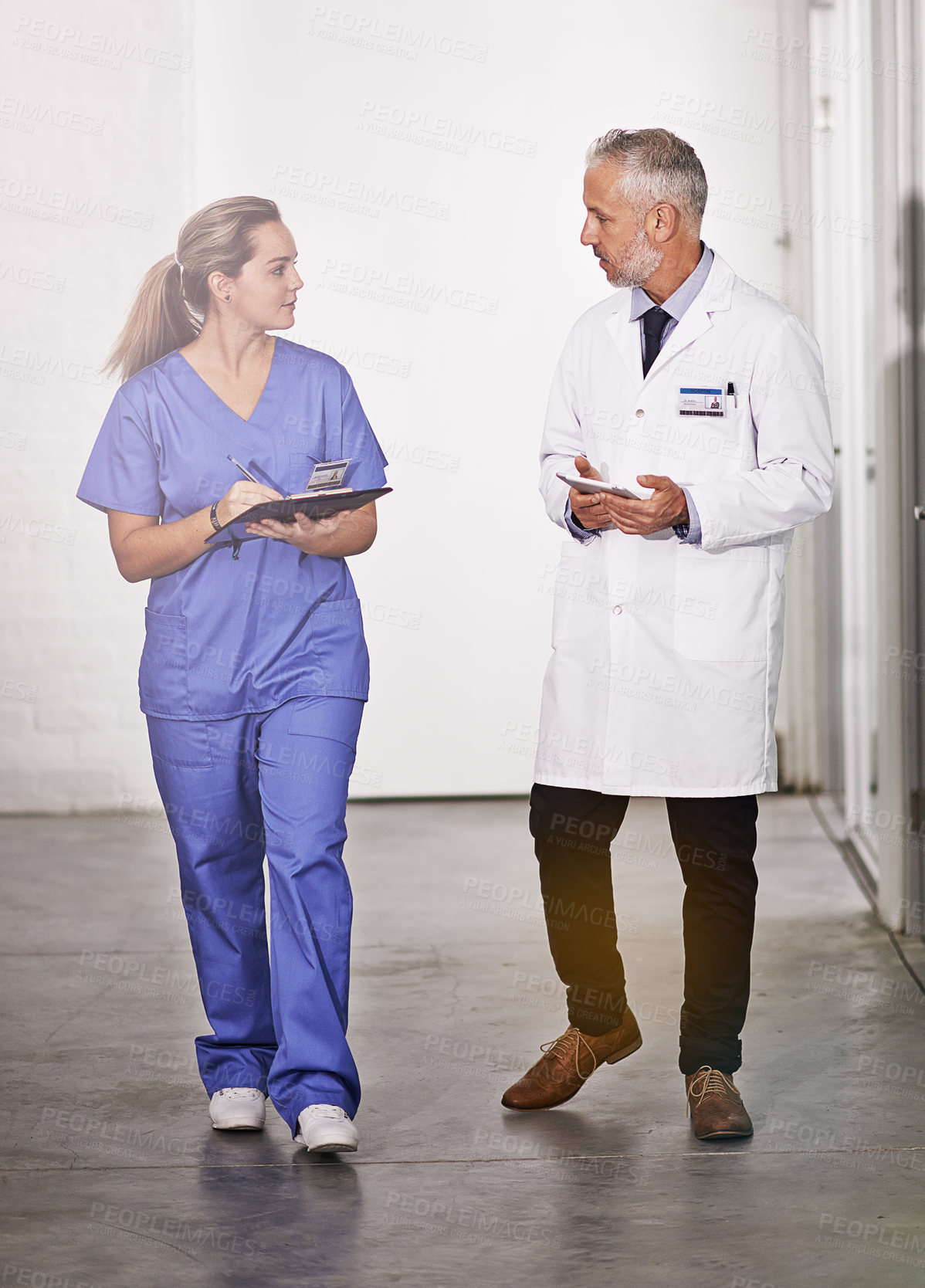 Buy stock photo Full length shot of a mature doctor teaching a female intern in the hospital corridor