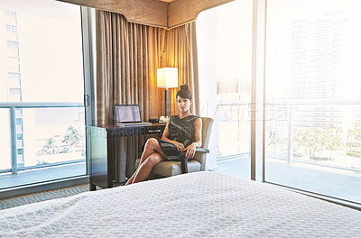 Buy stock photo Shot of a young businesswoman working in her hotel room