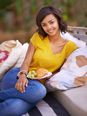 Buy stock photo Shot of a young woman enjoying a snack in the backard