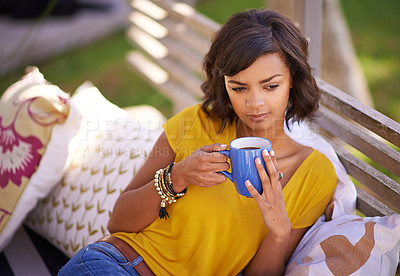 Buy stock photo Shot of a young woman relaxing with a beverage in the backyard