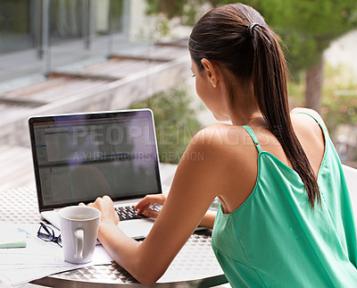 Buy stock photo Rearview shot of a young woman working on her laptop outside