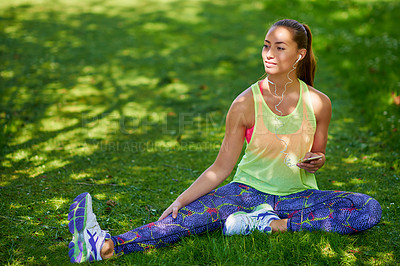 Buy stock photo Shot of a young woman listening to music on her phone while working out