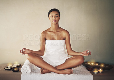 Buy stock photo Full length shot of a young woman meditating on a massage table at the spa