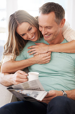 Buy stock photo Happy couple, love and newspaper with coffee in house and bonding together with care in marriage. Man, woman and hug by cappuccino for reading headlines, sofa and romantic indoor to relax on weekend