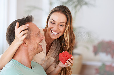 Buy stock photo Cropped shot of a woman surprising her husband with a gift