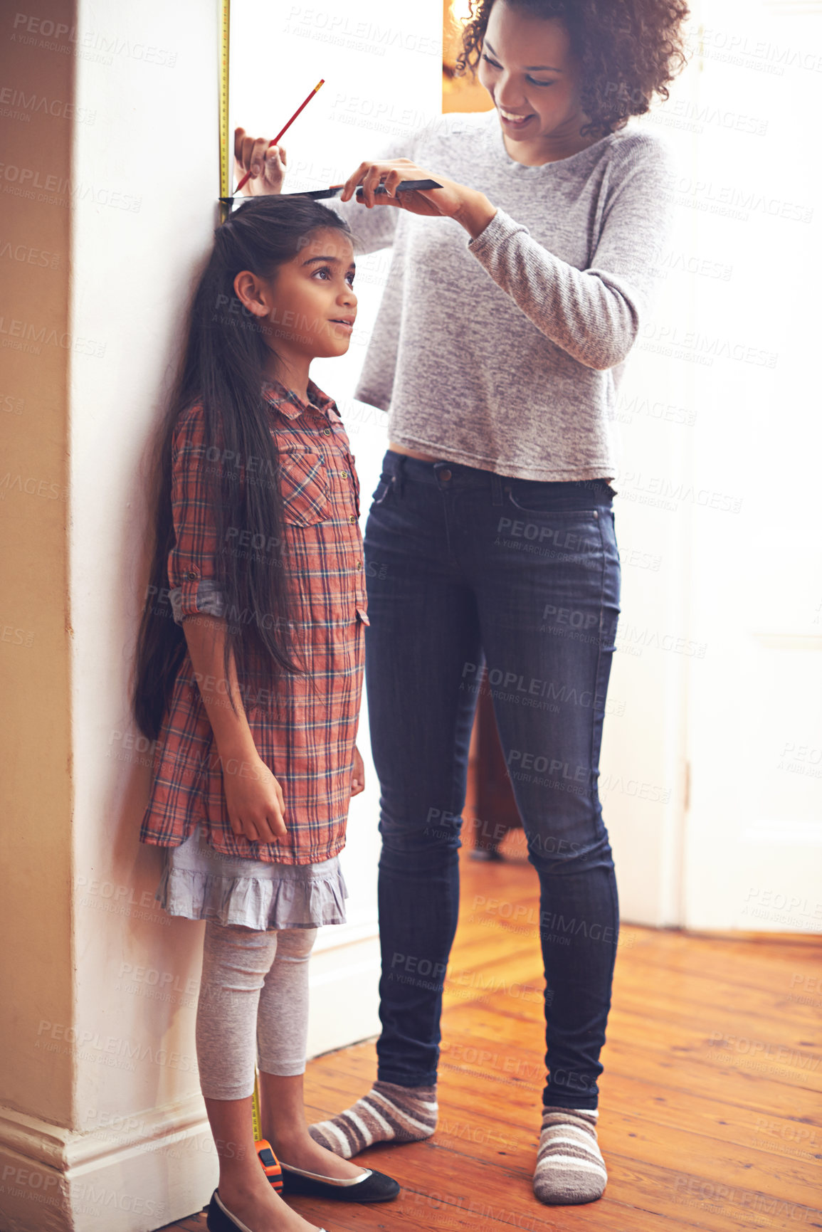 Buy stock photo Mother, child and measuring tape for height with ruler at wall for growth development in home, childhood or bonding. Female person, daughter and pencil in apartment for size checking, youth or parent