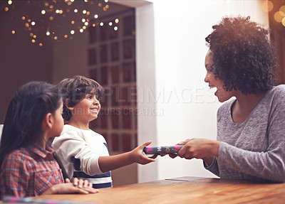 Buy stock photo Mom, children and happy in table with gift as birthday present with smile, support and bonding. Home, family and excited together in living room for childhood memories, care for love and siblings
