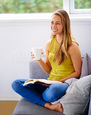 Buy stock photo Shot of a young woman reading a book on her sofa at home