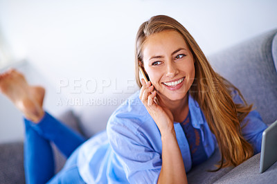 Buy stock photo Shot of a young woman talking on her cellphone while holding a digital tablet