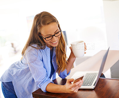 Buy stock photo A young woman having coffee while sitting with her laptop and cellphone