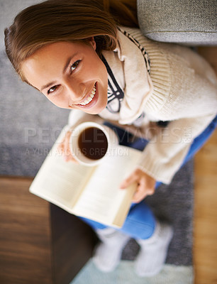 Buy stock photo High angle shot of a young woman having coffee while reading a book
