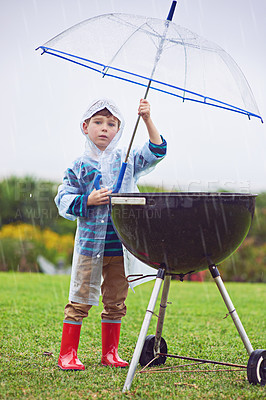 Buy stock photo Full length portrait of a young boy standing in front of an outdoor grill in the rain