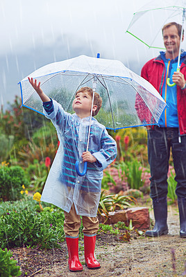 Buy stock photo Full length shot of a father and his son standing outside in the rain