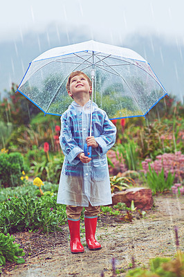 Buy stock photo Full length shot of a young boy standing outside in the rain