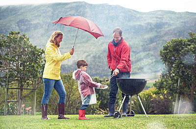 Buy stock photo Shot of a family having a barbecue outside in rainy weather