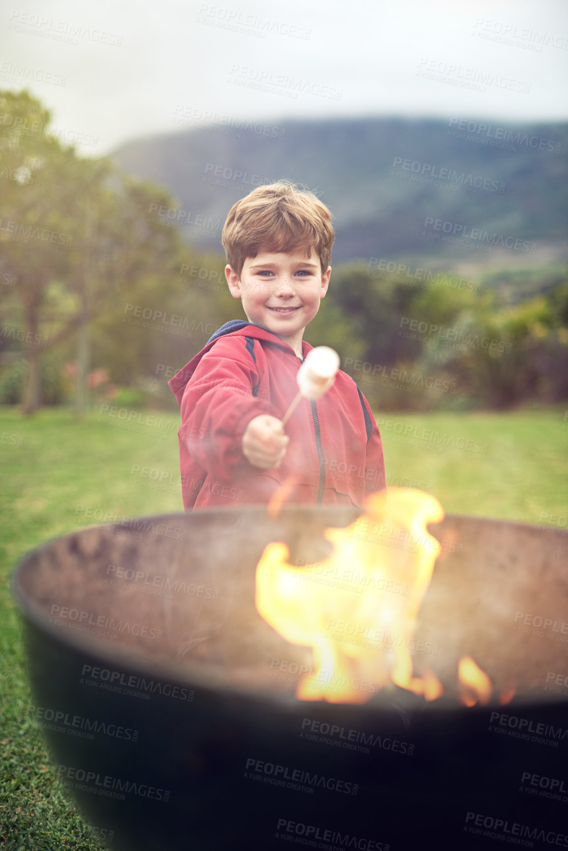 Buy stock photo Portrait of a little boy roasting a marshmallow over a fire