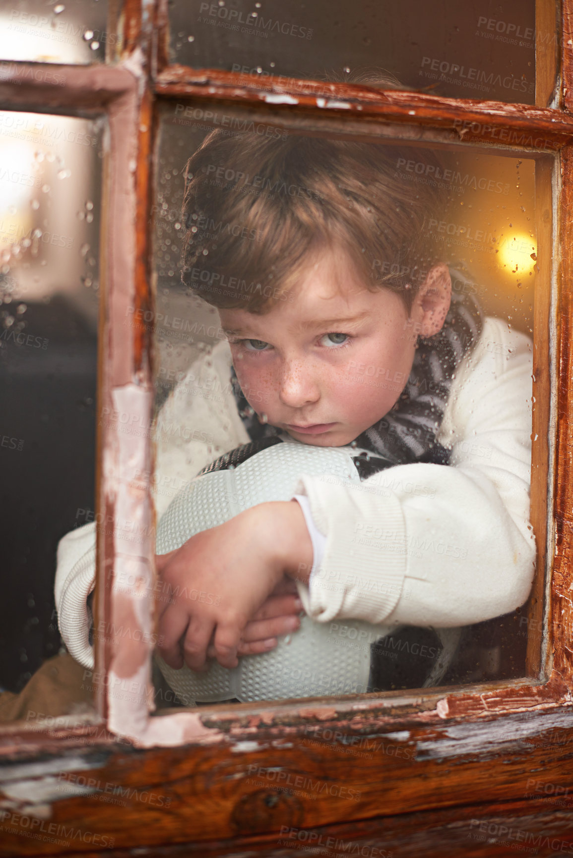 Buy stock photo Portrait, depression and sad child by window with anxiety for harassment, soccer ball and fear with bullying. Bored, lonely and face of young boy by glass with football and winter weather in Ireland