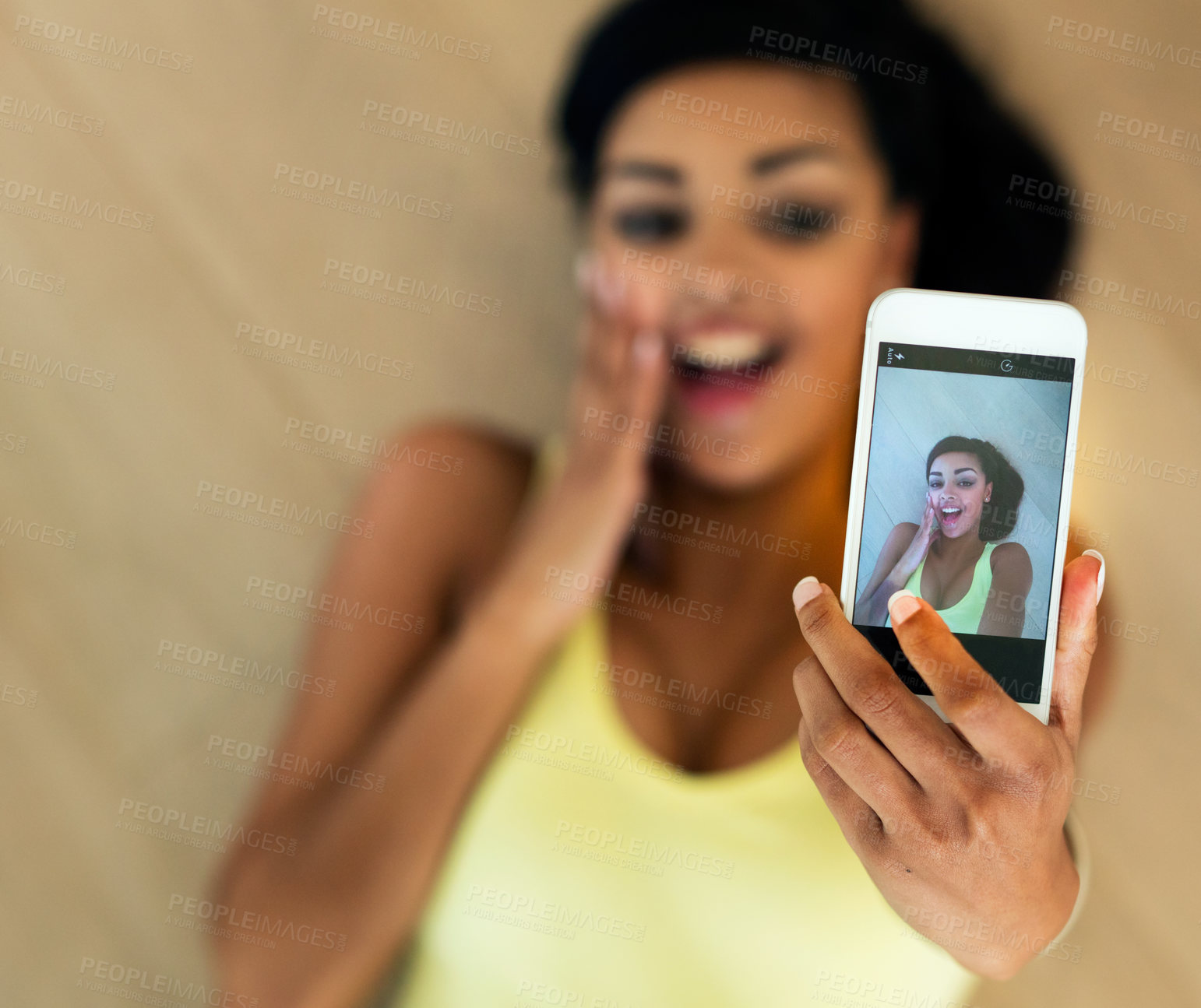 Buy stock photo Shot of a young woman taking a selfie while lying on a wooden floor