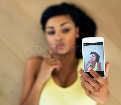 Buy stock photo Shot of a young woman taking a selfie while lying on a wooden floor