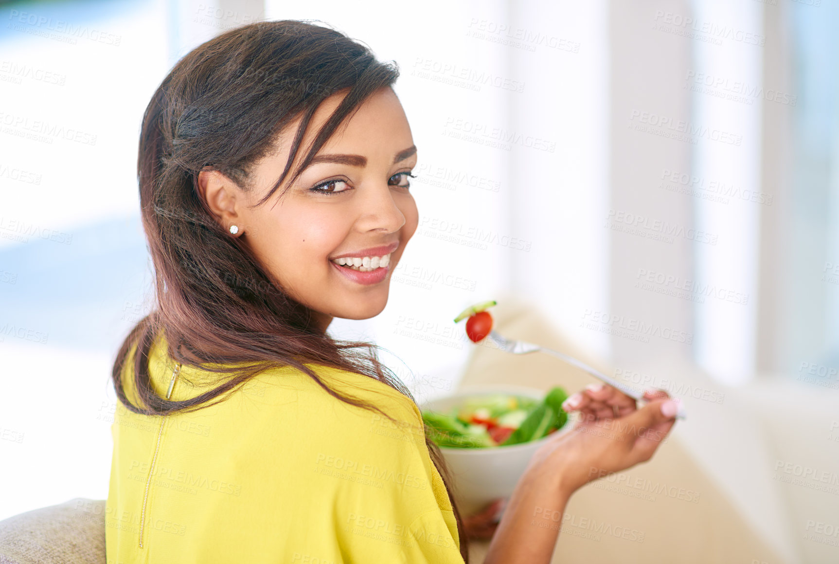 Buy stock photo Shot of a young woman eating a salad at home