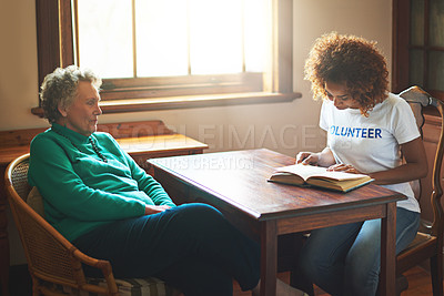 Buy stock photo Shot of a volunteer reading to a senior woman at a retirement home
