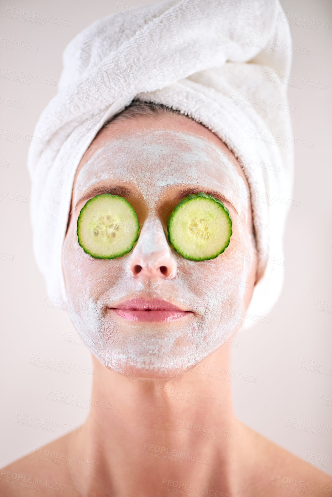 Buy stock photo Spa, woman and cucumber facial for skincare in studio with skin mask, organic detox or cosmetics with towel. Model, person or face with fruit for anti aging treatment or self care on white background