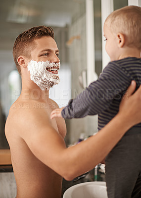 Buy stock photo Cropped shot of a man holding his baby while shaving in his bathroom