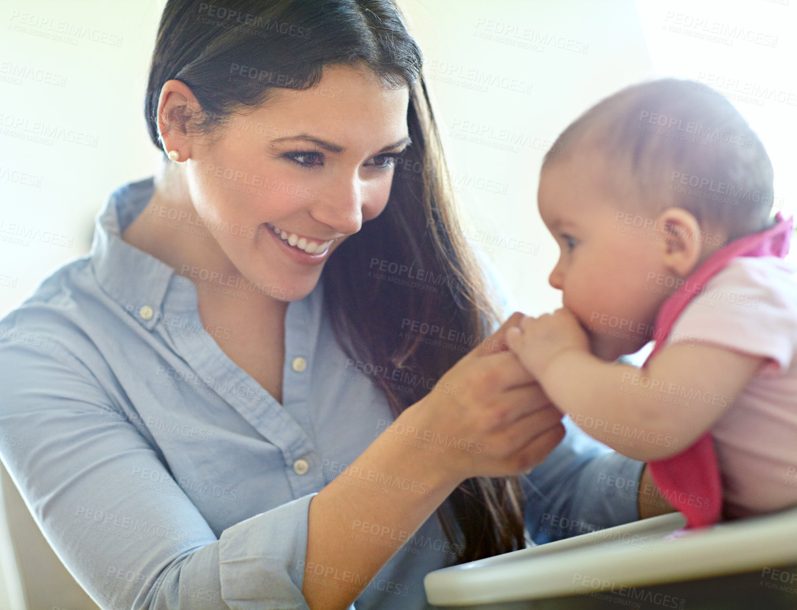 Buy stock photo Shot of a mother feeding her baby girl in a high chair