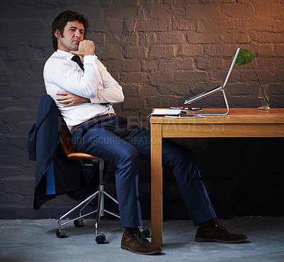 Buy stock photo Shot of a businessman looking thoughtful while sitting in his office late at night