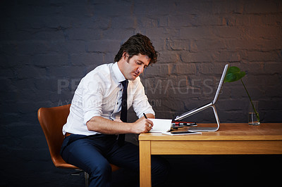 Buy stock photo Desk, investigation and notebook with detective man in office at night to work on criminal report. Brick wall, laptop and writing with mature investigator at table for evidence, justice or research